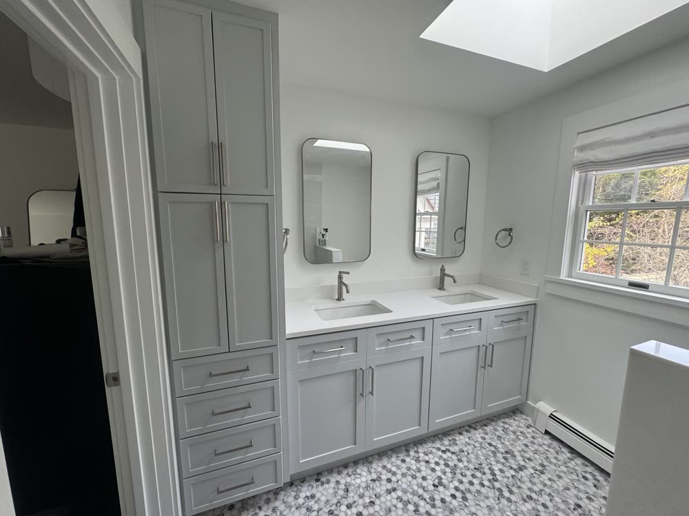 Double vanity and linen tower built to fit an irregular space